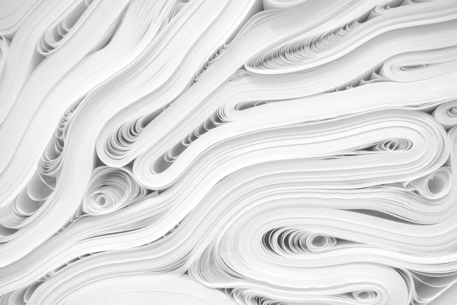 Long sheets of paper are stacked, folded and rolled together to make patterns of waves, circles and swirls.