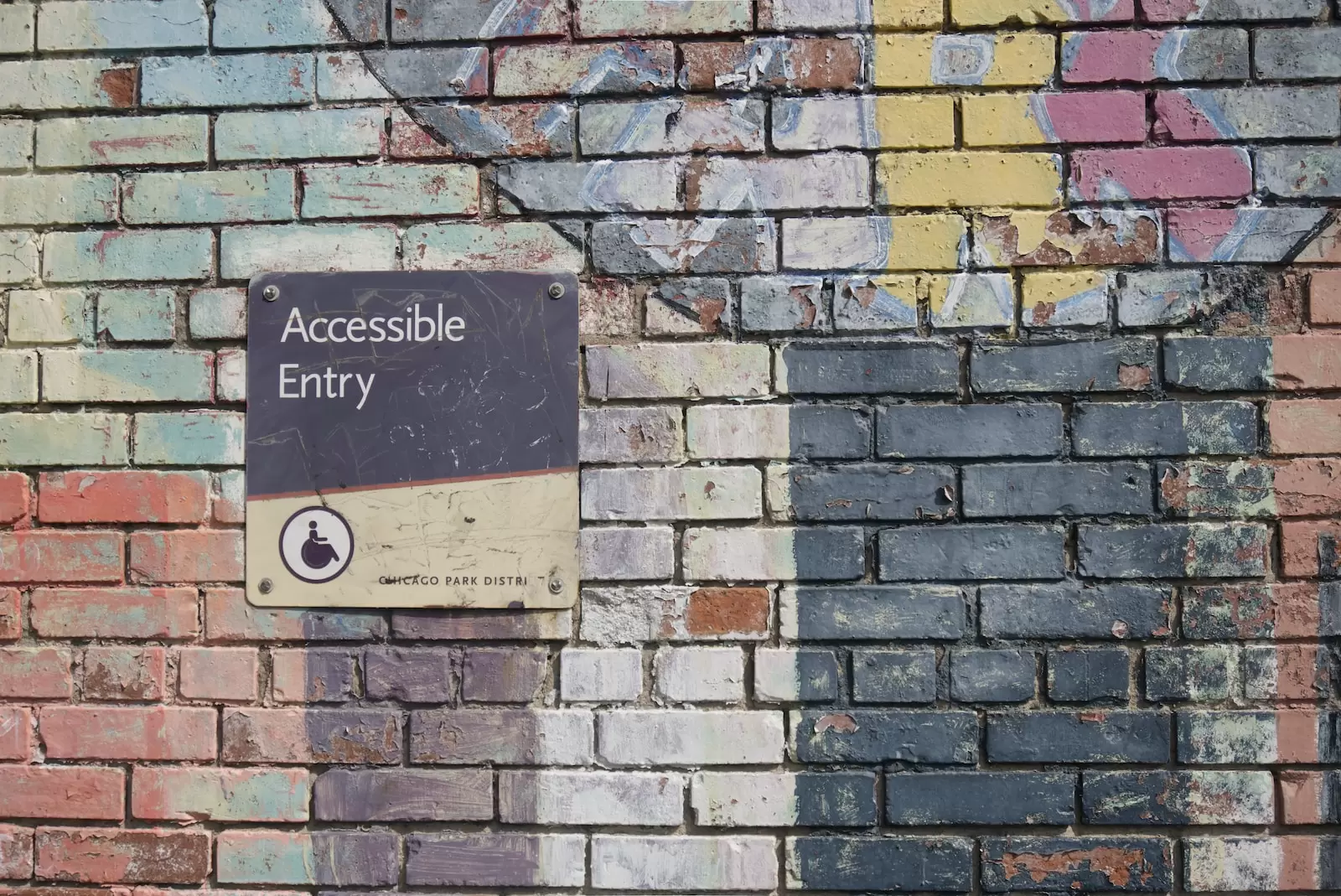 Black, white and red brick wall with "Accessible Entry" sign